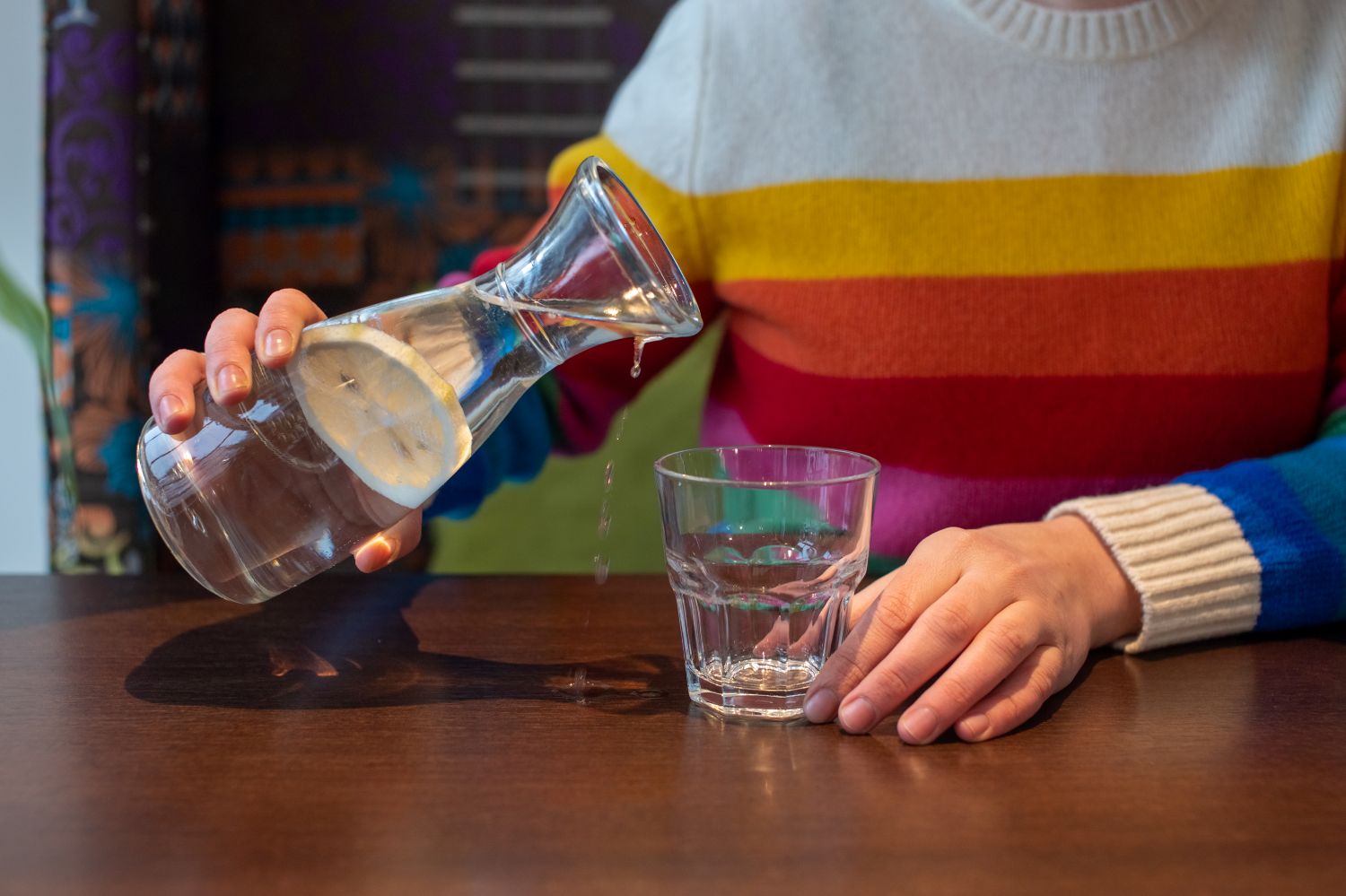 person pouring water into drinking glass